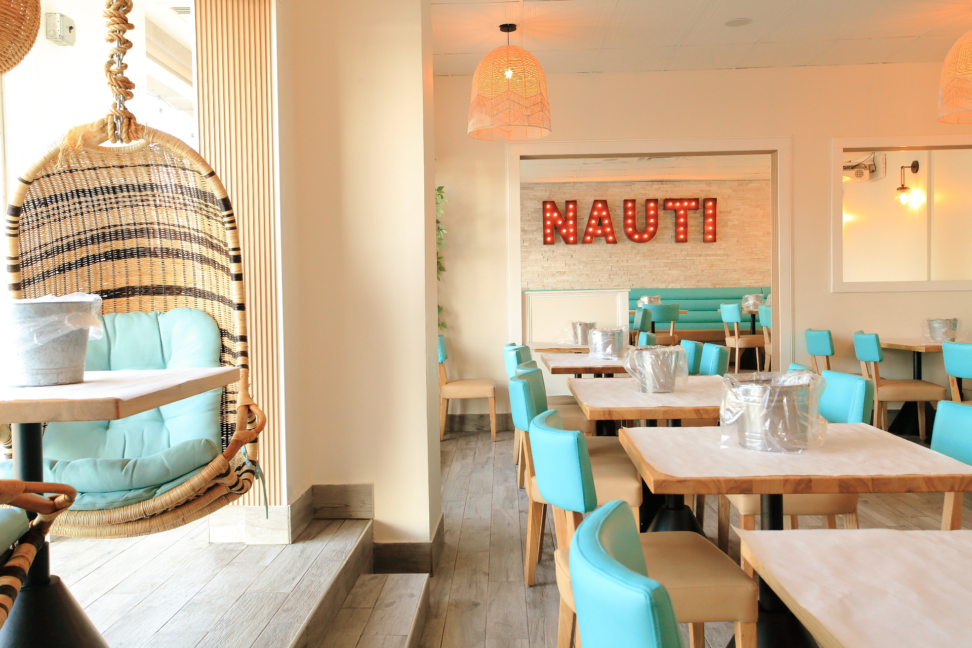Bright, beachy Nauti Cajun Crab dining room with turquoise seating and rattan accents
